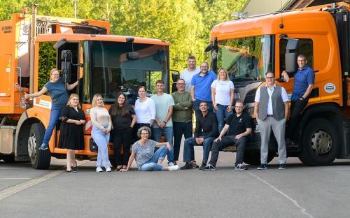 Gruppenfoto Verwaltungsmitarbeiter Betriebshof vor zwei Müllsammelfahrzeugen