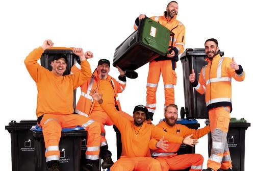 Sechs Müllwerker auf und vor verschiedenen Müllbehältern