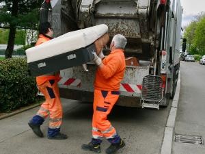 Zwei Mitarbeiter laden ein altes Sofa in das Sperrmüllfahrzeug.